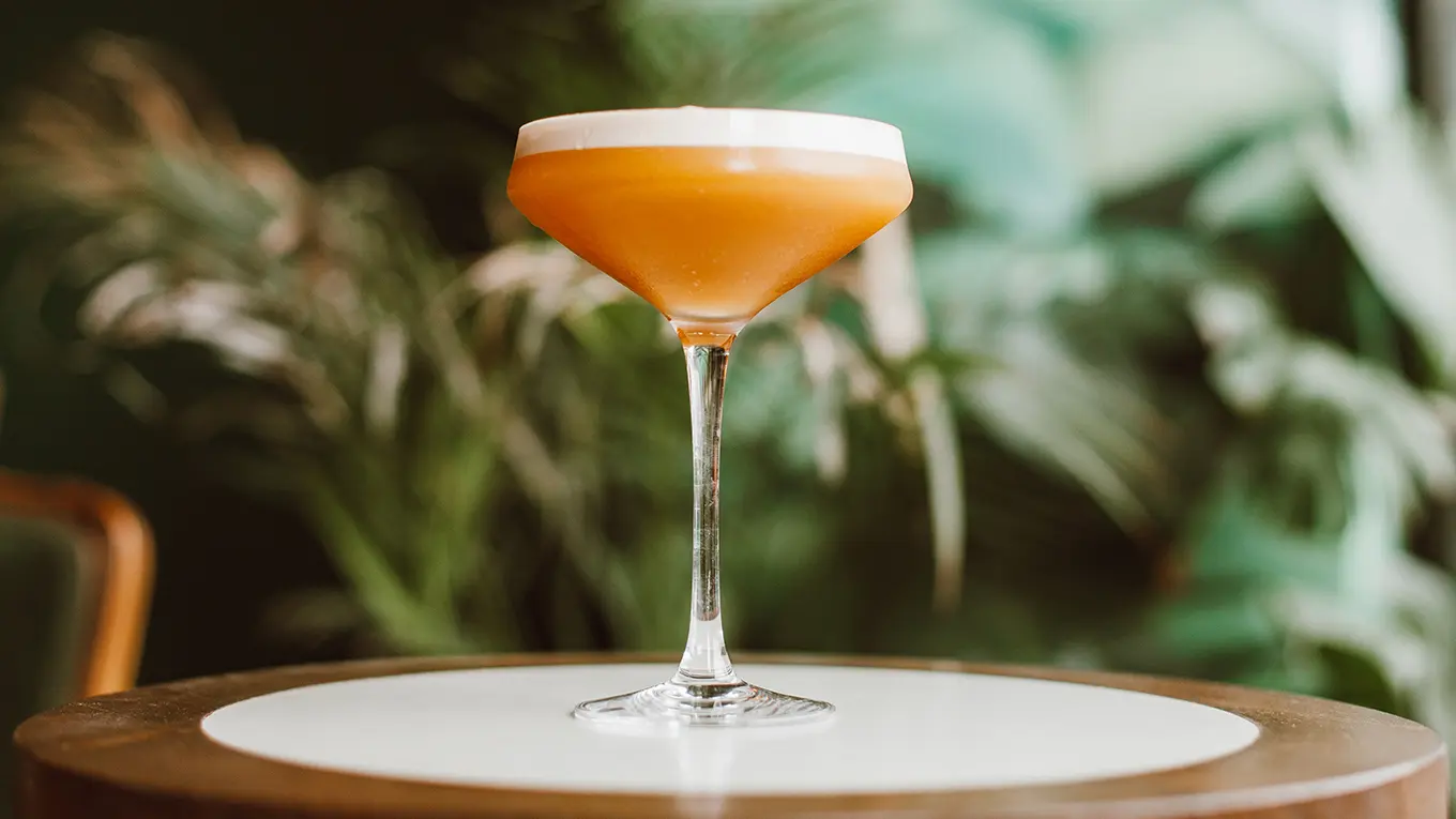 Aperol Sour Cocktail steht auf einem runden Tisch