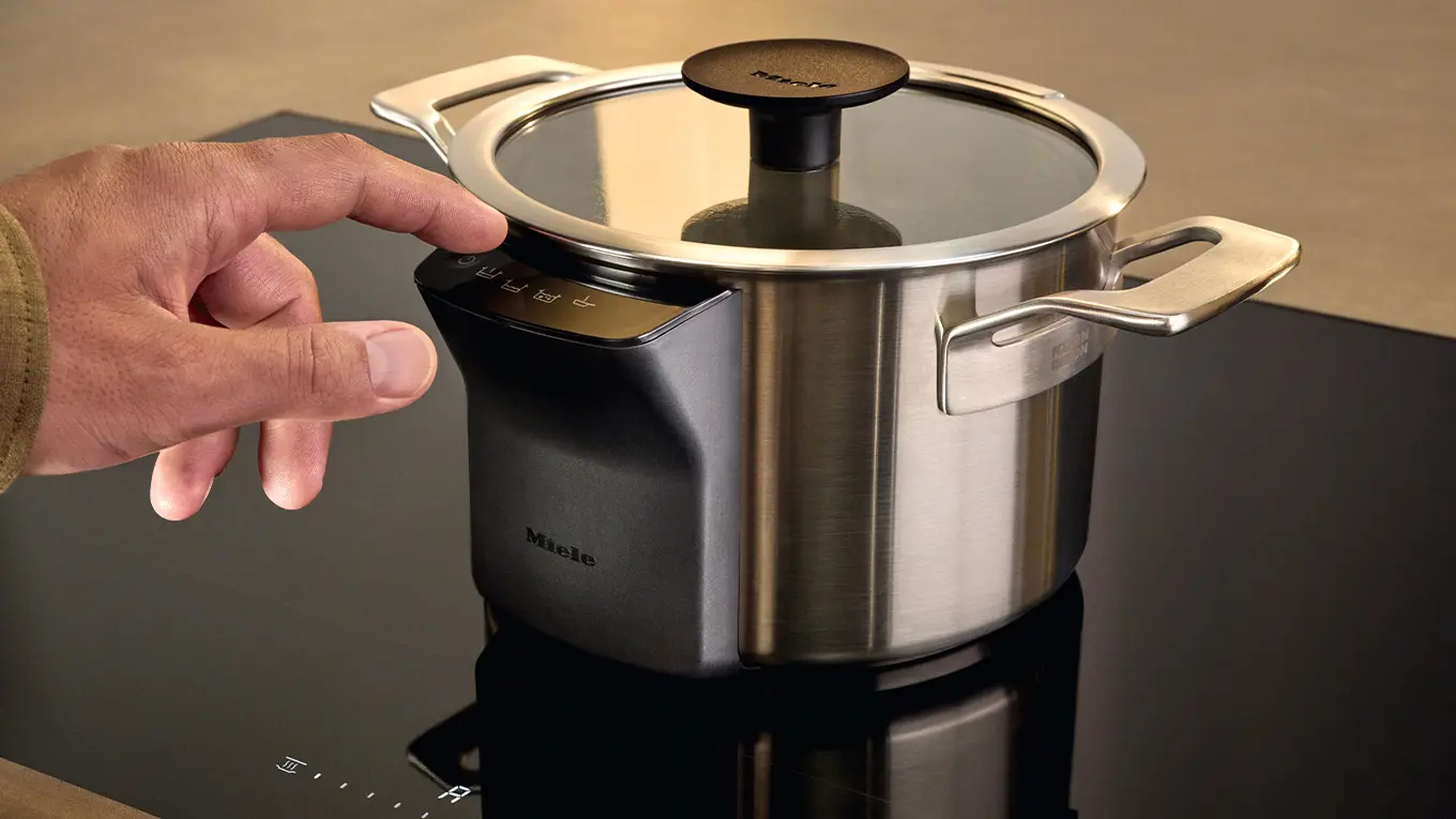 mann tippt mit dem finger auf den miele m sense kochtopf