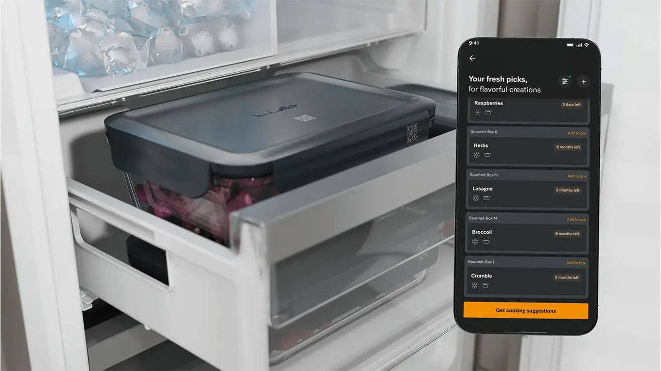 smartphone mit miele app vor einer gourmet box im gefrierschrank
