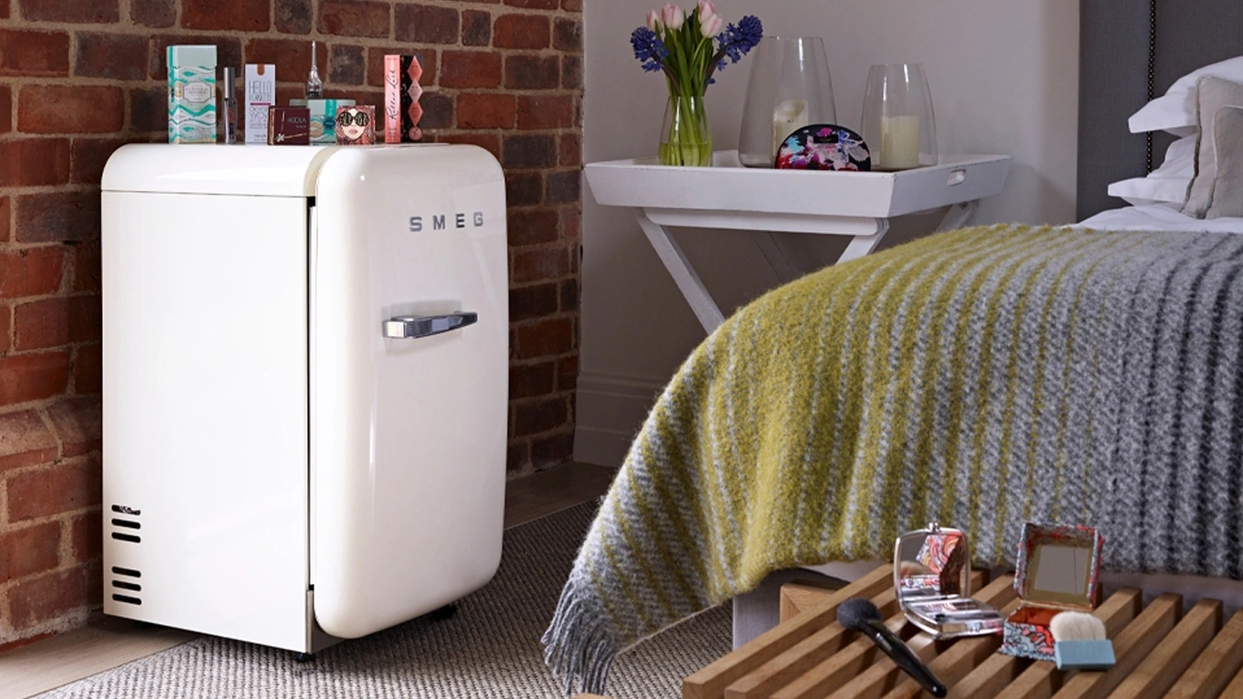 smeg retro mini kühlschrank fab5 in weiß von der Seite in einem Schlafzimmer neben dem Bett
