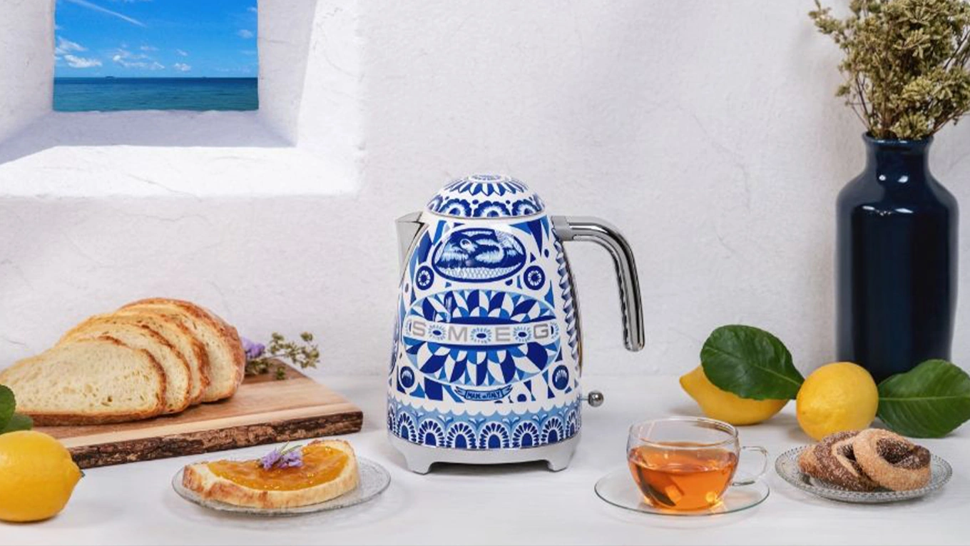 smeg dolce & gabbana blue mediterraneo wasserkocher in blau weiß retro look neben einer teetasse und brot