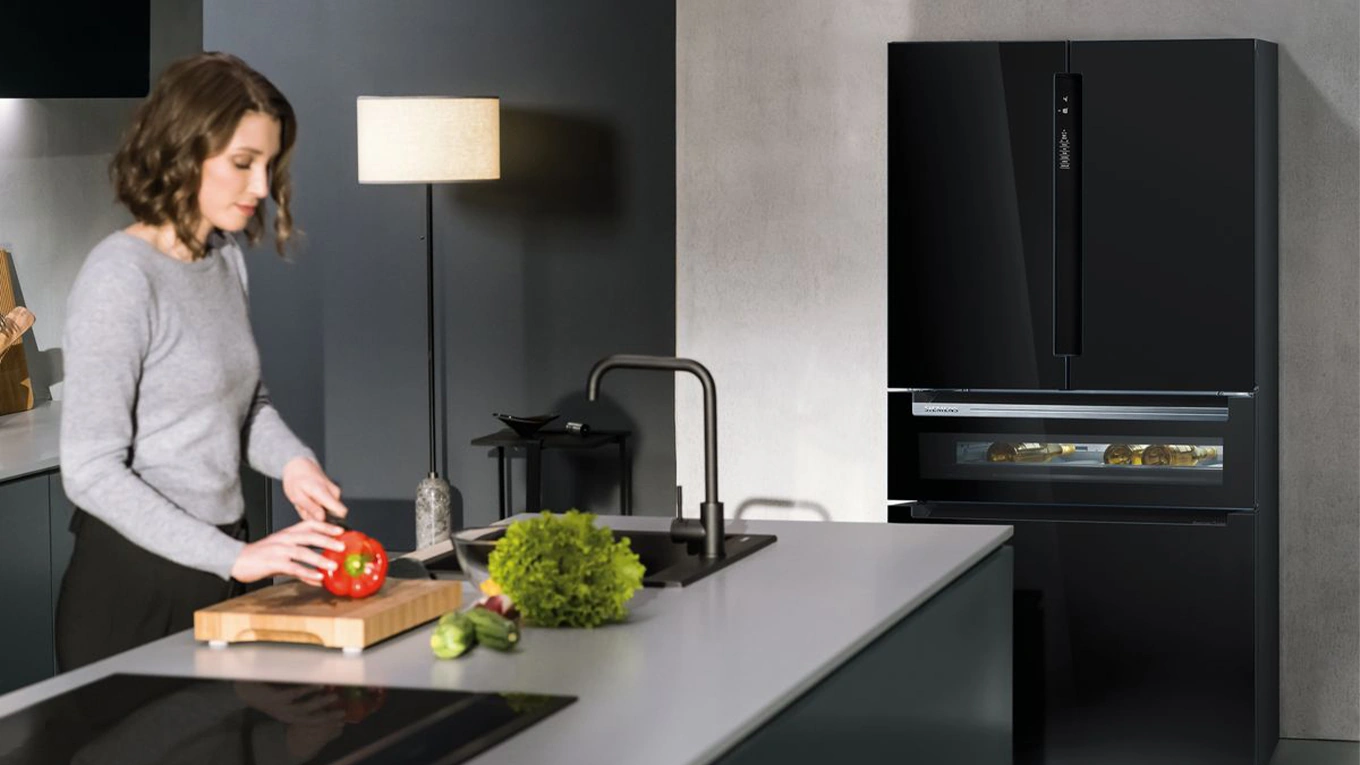 Siemens French Door Kühlschrank mit Getränkefach Frau beim Paprika schneiden in einer Küche mit Siemens French Door Kühlschrank mit Getränkefach in schwarz