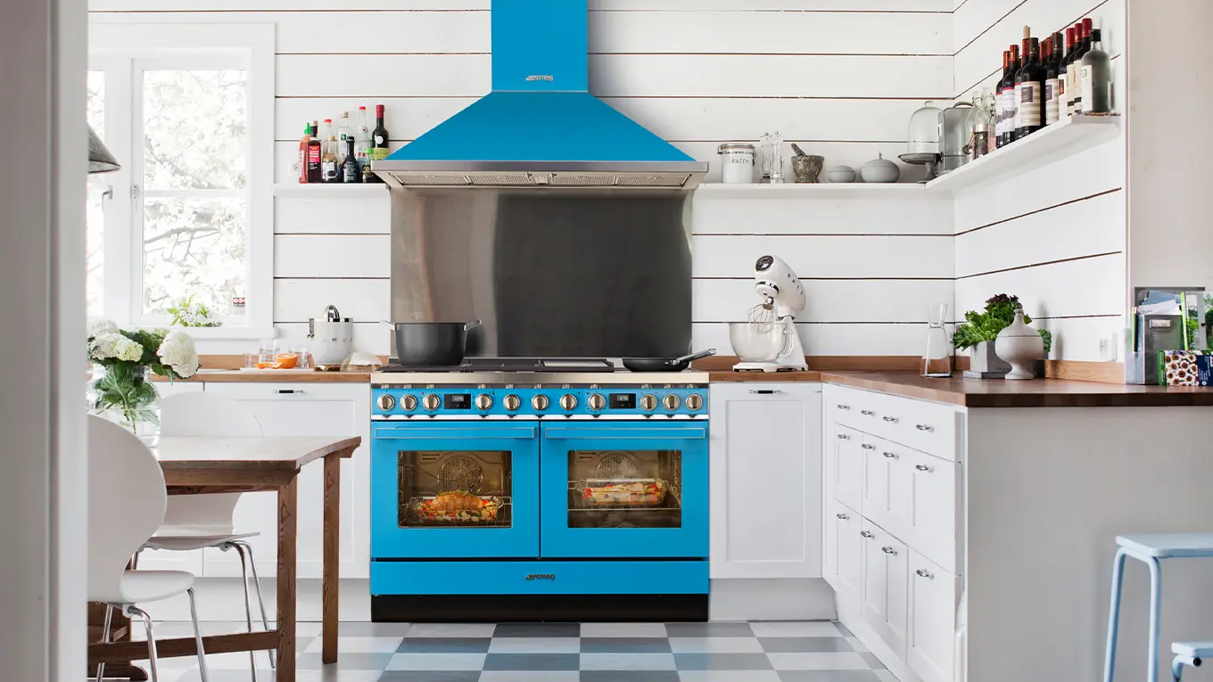 smeg standherd und dunstabzugshaube in blau in einer weißen küche