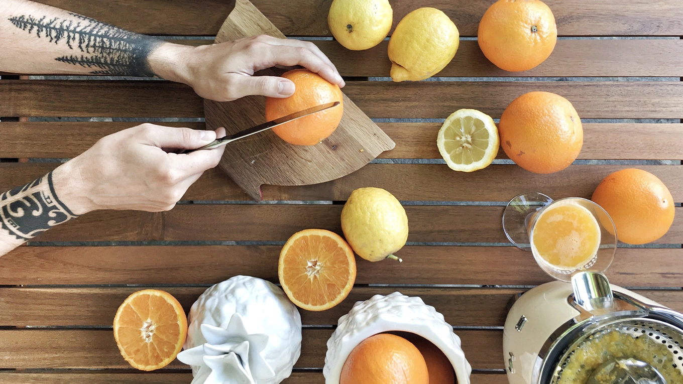 man halbiert orangen zum auspressen