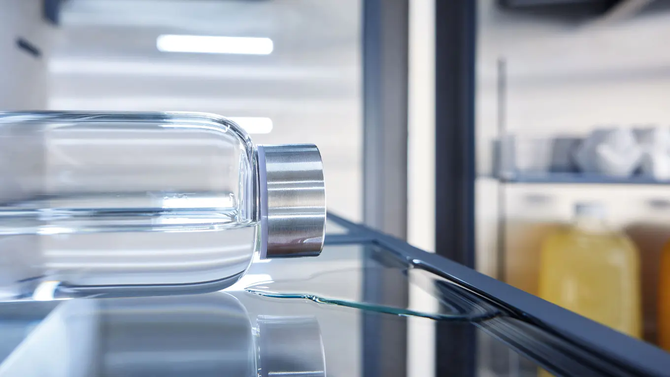 ausgelaufenes wasser aus einer glasflasche im miele kühlschrank