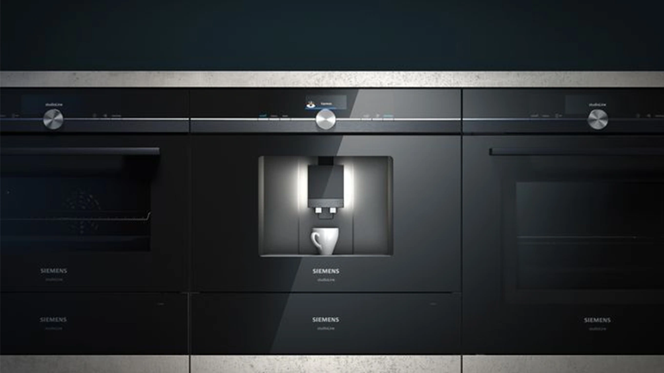 schwarzer siemens studioline kaffeevollautomat mit weißer Tasse neben Backöfen eingebaut