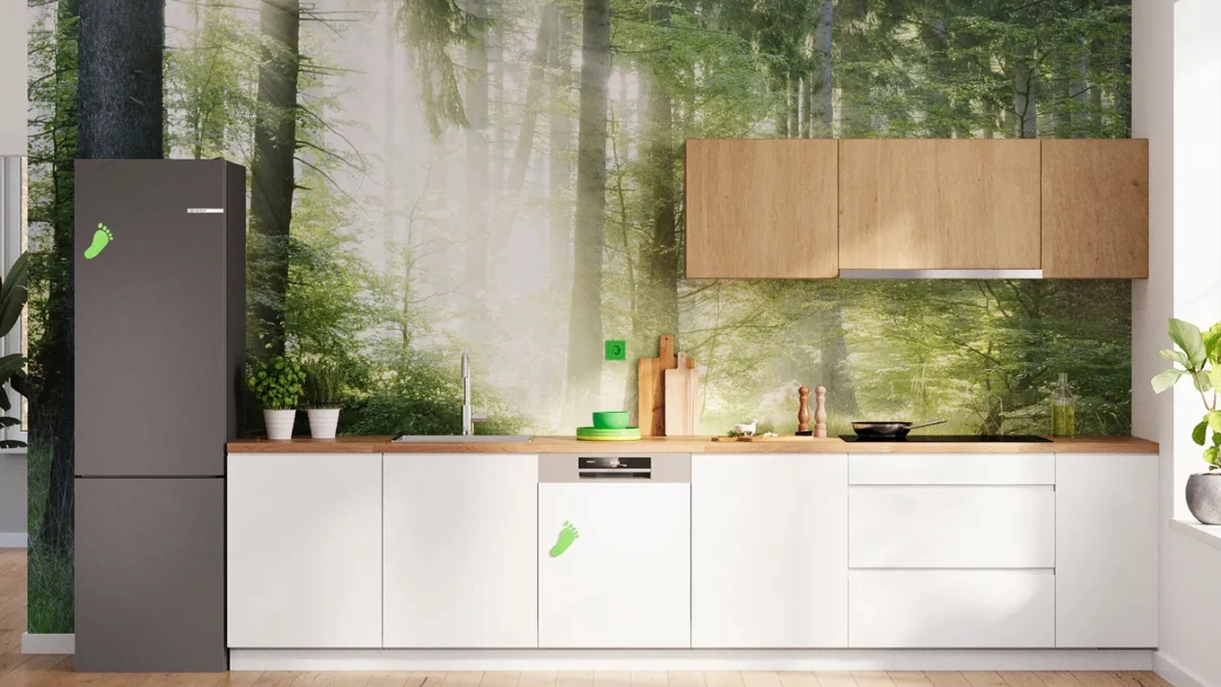 Bosch Green Collection Kühlschrank und weitere Küchengeräte in einer weißen Küche vor einer Wald Tapete