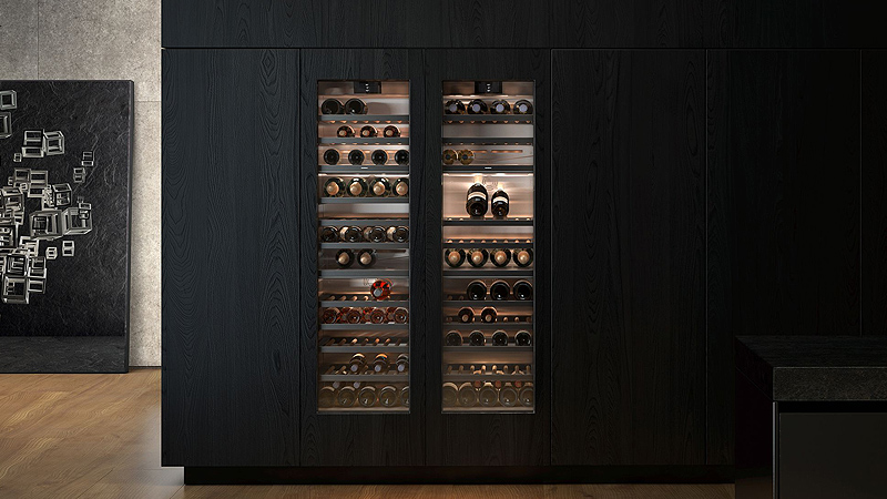 Zwei volle Vario Weinschraenke aus der Gaggenau Serie 400 mit leuchtendem warmen Licht in einer dunklen kueche 