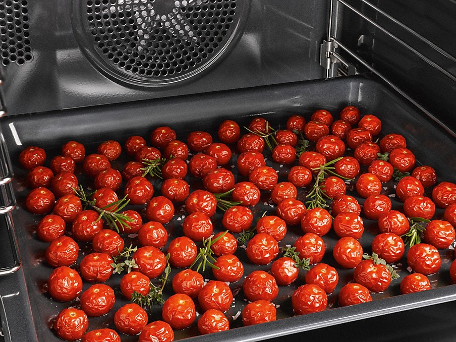 viele kleine gebackene tomaten auf einem backblech im miele backofen