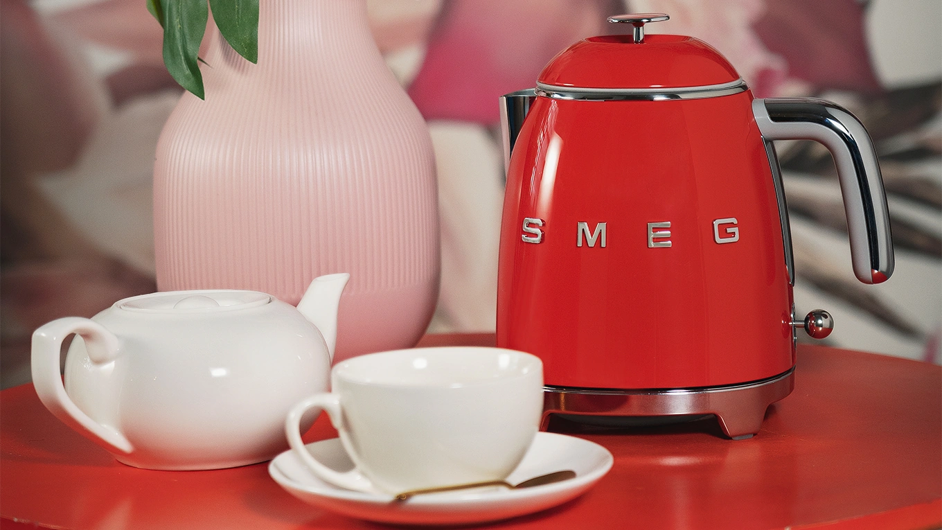 roter smeg wasserkocher mit weißer teetasse und kanne
