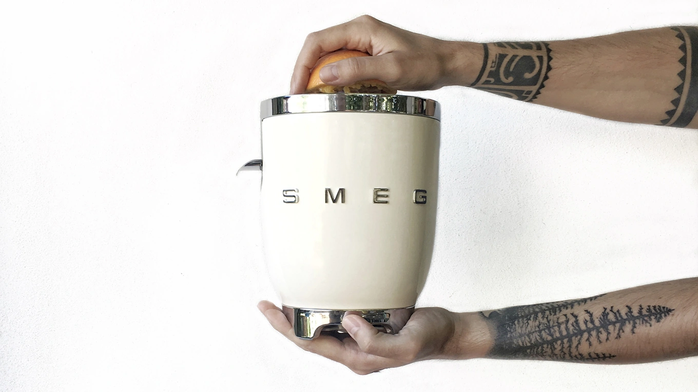 mann hält smeg zitruspresse in creme