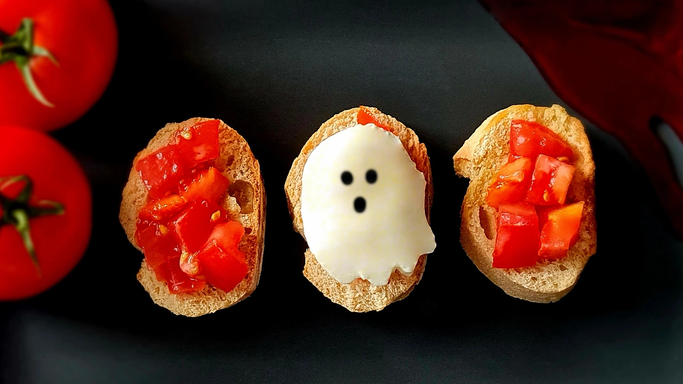 drei Stück Halloween Bruschetta Boo-Schetta mit Mozzarella in Geistform auf schwarzem Untergrund