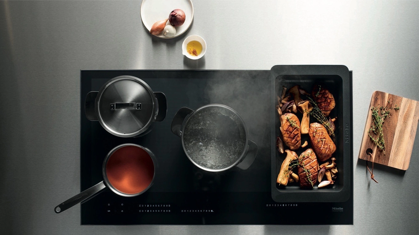 Viele Töpfe und Pfannen auf einem miele induktionskochfeld mit flex induktion von oben