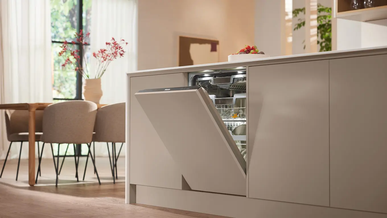 geöffneter miele geschirrspüler vollintegriert in einer beigen kücheninsel