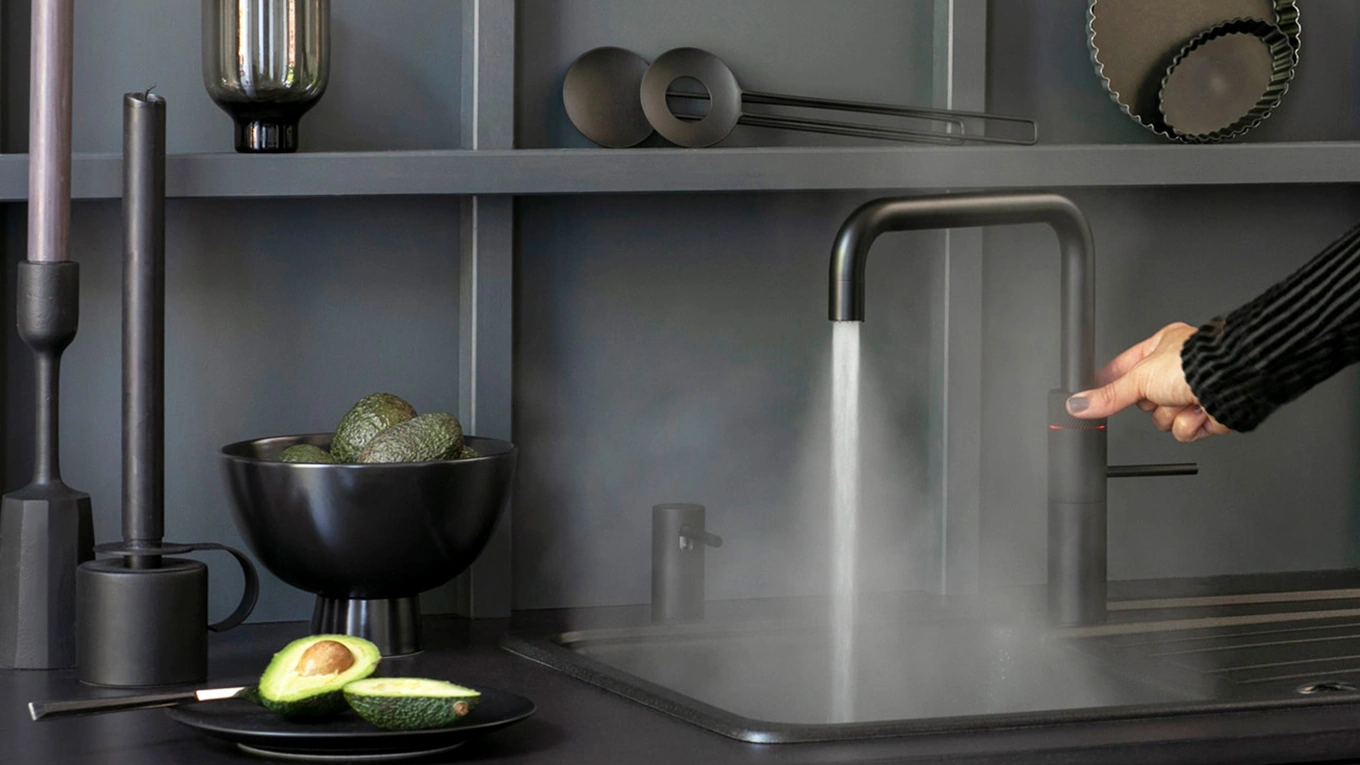 quooker wasserhahn eckig in schwarz in einer dunklen küche aus dem heißes wasser läuft