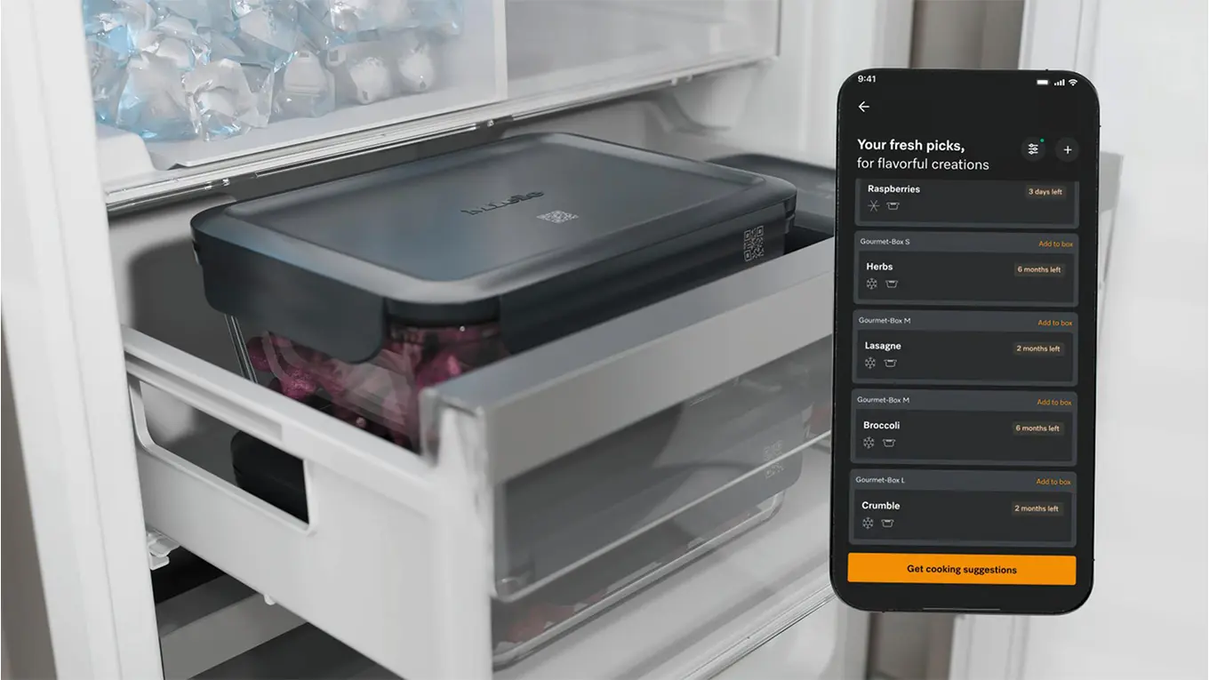 Smartphone mit miele app neben gourmet box mit qr code im gefrierschrank