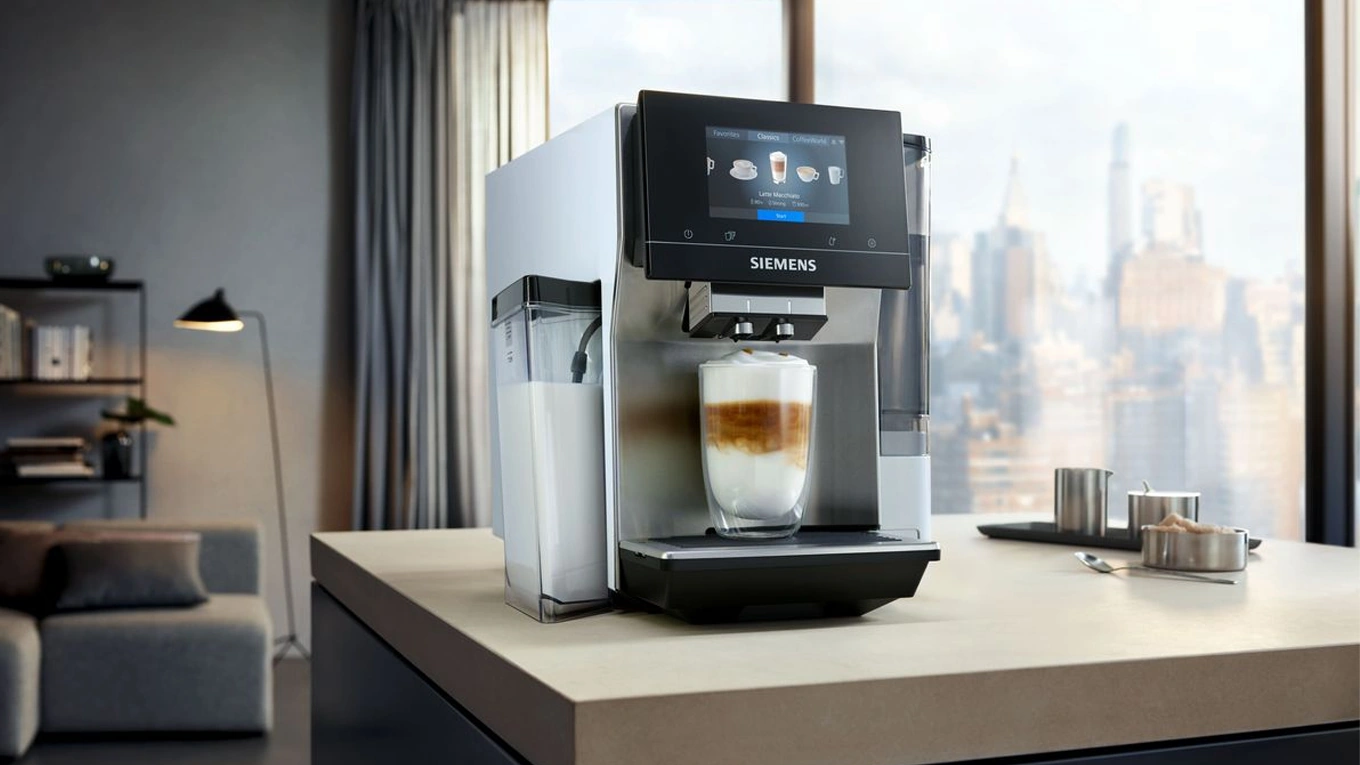 siemens eq.700 stand kaffeevollautomat mit gefülltem latte macchiato glas in einer küche mit skyline ausblick